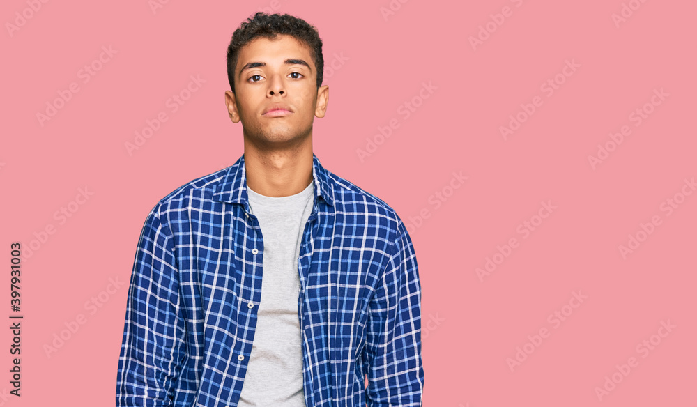 Young handsome african american man wearing casual clothes relaxed with serious expression on face. simple and natural looking at the camera. Young handsome african american man wearing casual clothes relaxed with serious expression on face. simple and natural looking at the camera.