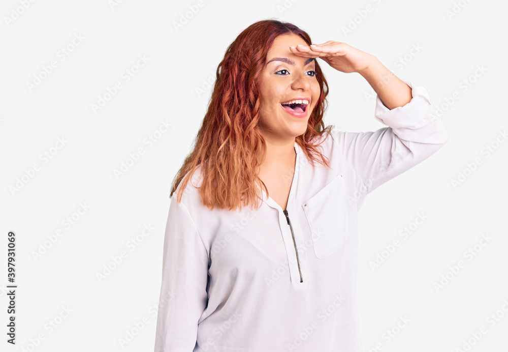 Young latin woman wearing casual clothes very happy and smiling looking far away with hand over head. searching concept. Young latin woman wearing casual clothes very happy and smiling looking far away with hand over head. searching concept.