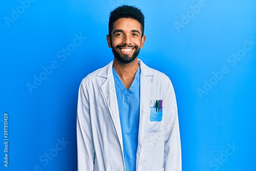 Handsome hispanic man with beard wearing doctor uniform with a happy and cool smile on face. lucky person.