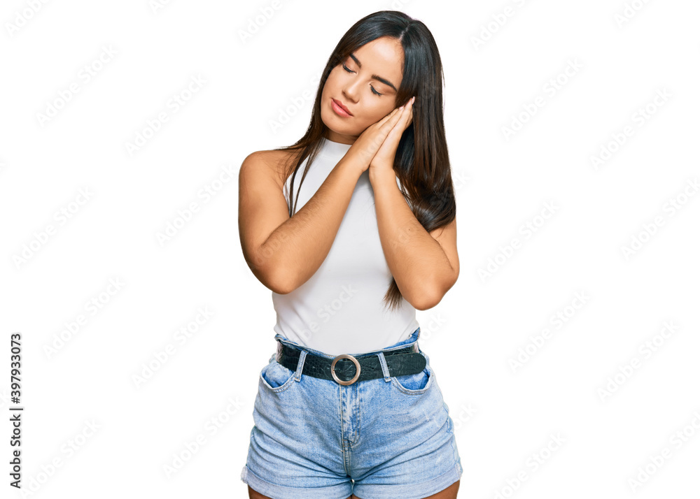 Young beautiful hispanic girl wearing casual clothes sleeping tired dreaming and posing with hands together while smiling with closed eyes. Young beautiful hispanic girl wearing casual clothes sleeping tired dreaming and posing with hands together while smiling with closed eyes.