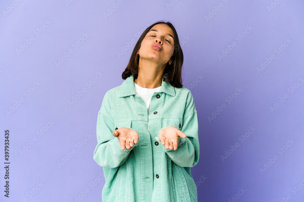 Young mixed race woman folding lips and holding palms to send air kiss. Young mixed race woman folding lips and holding palms to send air kiss.