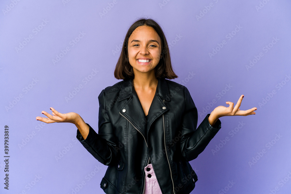 Young mixed race woman makes scale with arms, feels happy and confident. Young mixed race woman makes scale with arms, feels happy and confident.