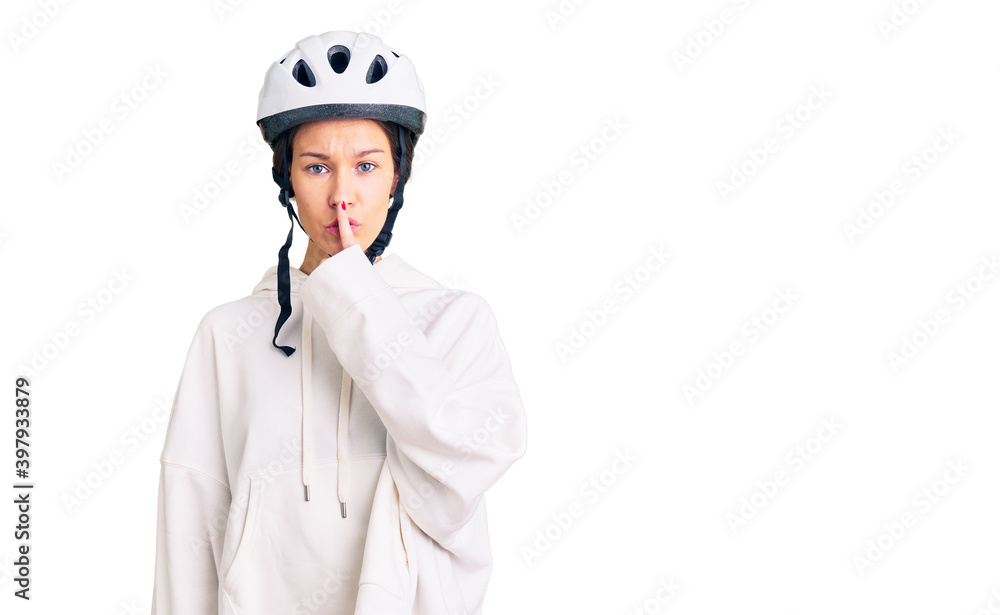 Beautiful brunette young woman wearing bike helmet and sporty clothes asking to be quiet with finger on lips. silence and secret concept. Beautiful brunette young woman wearing bike helmet and sporty clothes asking to be quiet with finger on lips. silence and secret concept.