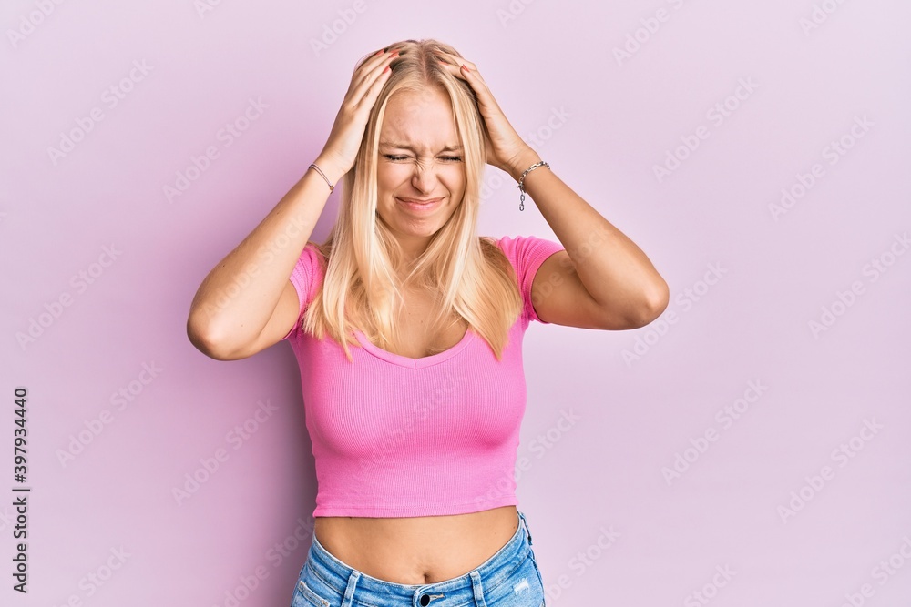 Young blonde girl wearing casual clothes suffering from headache desperate and stressed because pain and migraine. hands on head. Young blonde girl wearing casual clothes suffering from headache desperate and stressed because pain and migraine. hands on head.