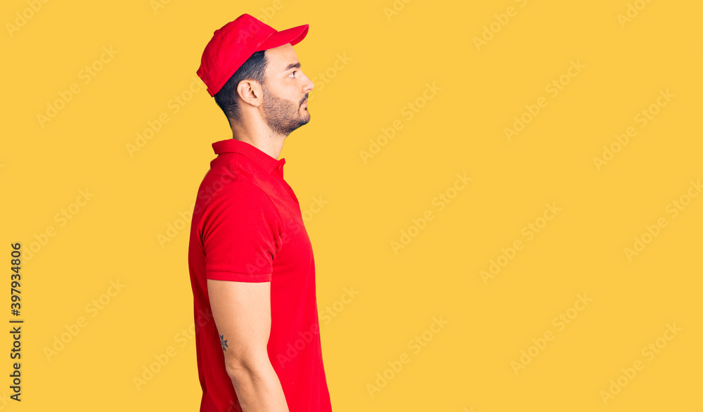 Young handsome hispanic man wearing delivery courier uniform looking to side, relax profile pose with natural face with confident smile.