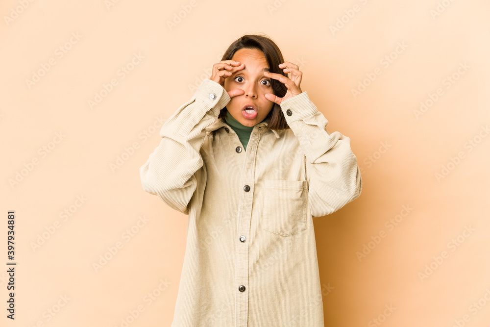 Young hispanic woman isolated keeping eyes opened to find a success opportunity. Young hispanic woman isolated keeping eyes opened to find a success opportunity.
