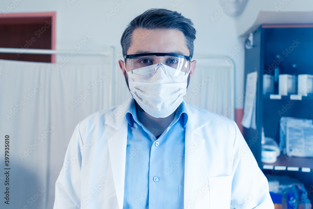 Young Scientist Checking Test Tubes In The Lab. Man Wears Protective Goggles Young Scientist Checking Test Tubes In The Lab. Man Wears Protective Goggles