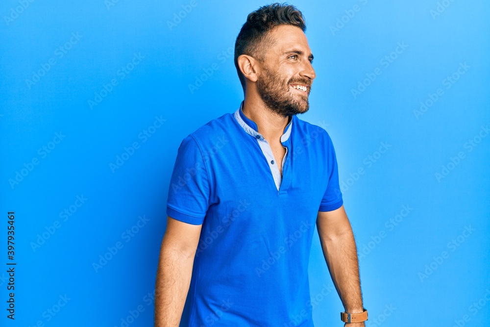 Handsome man with beard wearing casual clothes looking away to side with smile on face, natural expression. laughing confident. Handsome man with beard wearing casual clothes looking away to side with smile on face, natural expression. laughing confident.