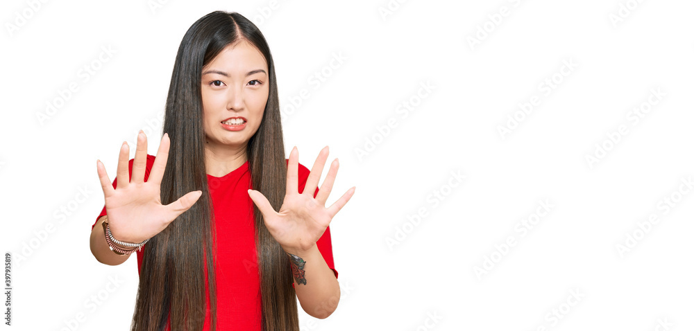 Young chinese woman wearing casual clothes afraid and terrified with fear expression stop gesture with hands, shouting in shock. panic concept. Young chinese woman wearing casual clothes afraid and terrified with fear expression stop gesture with hands, shouting in shock. panic concept.