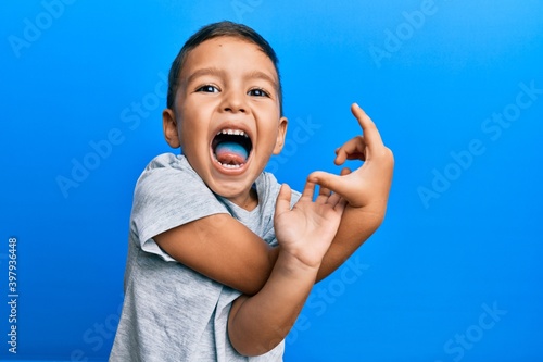 Adorable latin toddler showing blue tongue standing over isolated background. photo