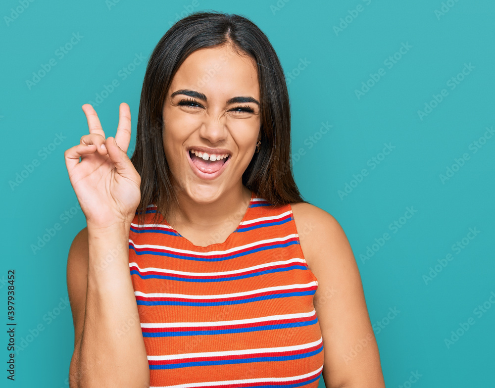 Young brunette woman wearing casual clothes smiling with happy face winking at the camera doing victory sign. number two. Young brunette woman wearing casual clothes smiling with happy face winking at the camera doing victory sign. number two.
