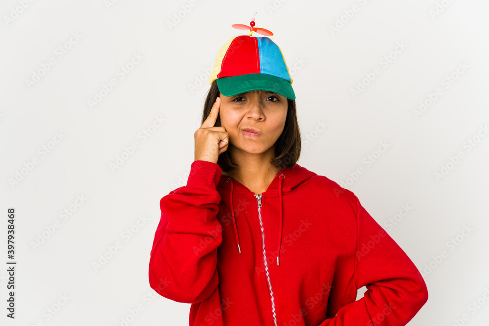 Young hispanic woman wearing a cap with propeller isolated pointing temple with finger, thinking, focused on a task. Young hispanic woman wearing a cap with propeller isolated pointing temple with finger, thinking, focused on a task.