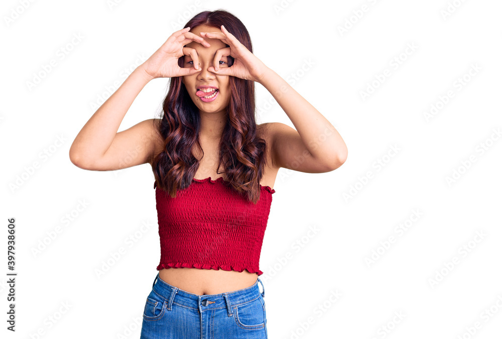 Young beautiful chinese girl wearing casual clothes doing ok gesture like binoculars sticking tongue out, eyes looking through fingers. crazy expression. Young beautiful chinese girl wearing casual clothes doing ok gesture like binoculars sticking tongue out, eyes looking through fingers. crazy expression.