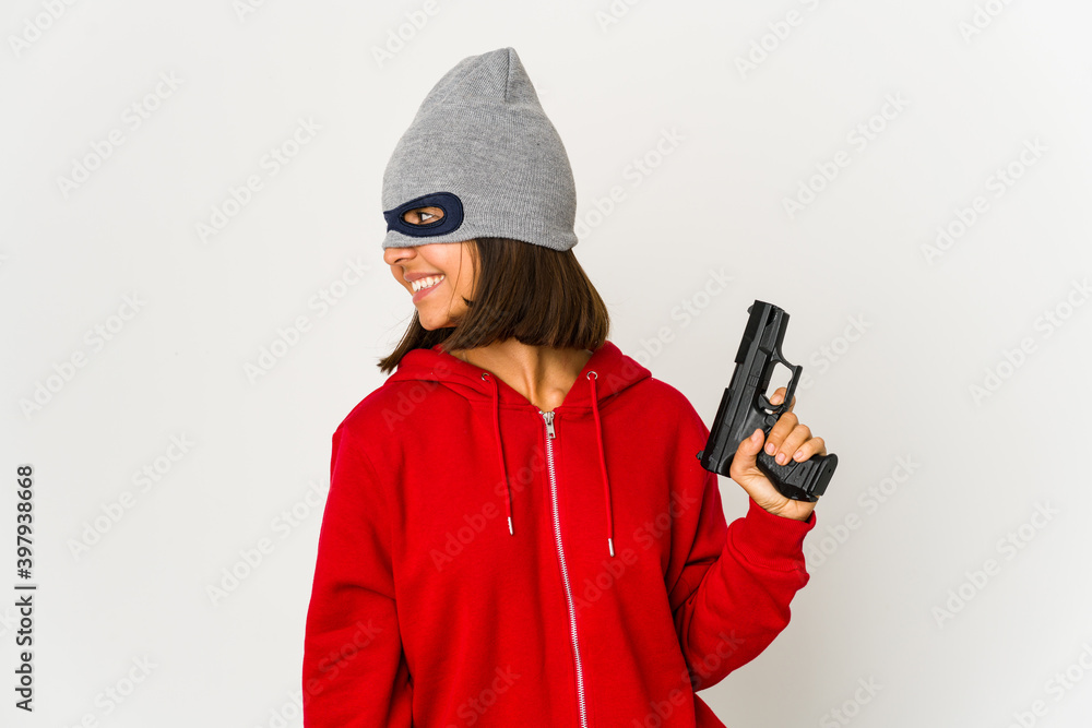 Young robber hispanic woman wearing a mask looks aside smiling, cheerful and pleasant. Young robber hispanic woman wearing a mask looks aside smiling, cheerful and pleasant.