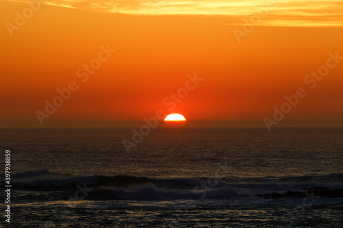 sunset with the reddish sun near the sea © Imaxepress