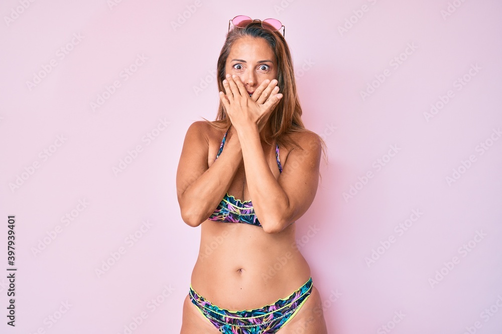 Middle age hispanic woman wearing bikini shocked covering mouth with hands for mistake. secret concept. Middle age hispanic woman wearing bikini shocked covering mouth with hands for mistake. secret concept.