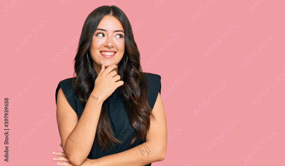 Beautiful brunette young woman wearing black shirt with hand on chin thinking about question, pensive expression. smiling with thoughtful face. doubt concept. Beautiful brunette young woman wearing black shirt with hand on chin thinking about question, pensive expression. smiling with thoughtful face. doubt concept.
