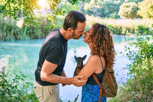 Middle age couple wearing casual clothes standing around river holding chihuahua dog at the park © Krakenimages.com