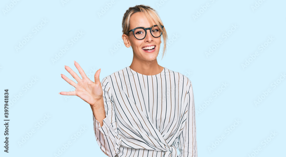 Beautiful blonde woman wearing business shirt and glasses showing and pointing up with fingers number five while smiling confident and happy.