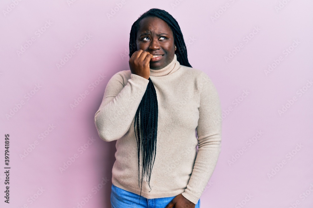 Fototapeta premium Young black woman with braids wearing casual winter sweater looking stressed and nervous with hands on mouth biting nails. anxiety problem.