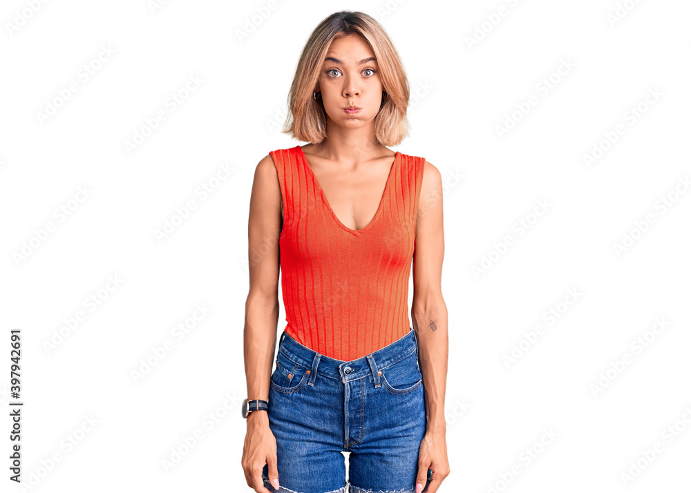 Obraz premium Beautiful caucasian woman wearing casual clothes puffing cheeks with funny face. mouth inflated with air, crazy expression.