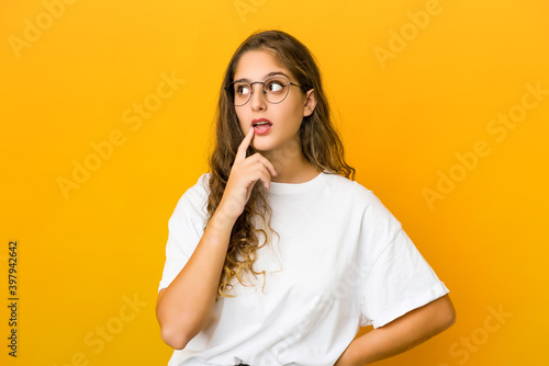 Young caucasian woman looking sideways with doubtful and skeptical expression.