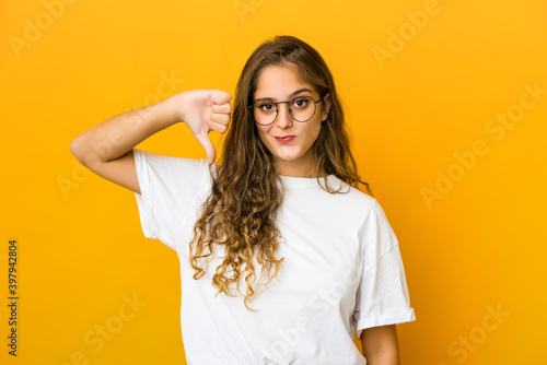 Young caucasian woman showing thumb down, disappointment concept.