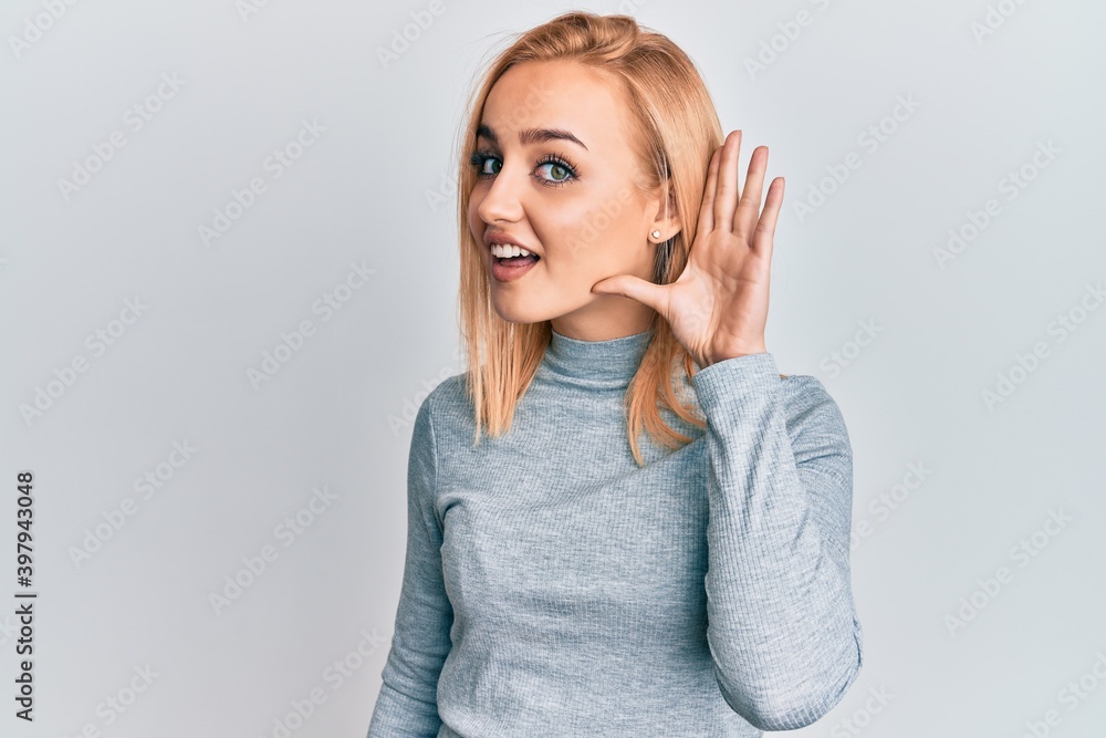Beautiful caucasian woman wearing casual clothes smiling with hand over ear listening and hearing to rumor or gossip. deafness concept. Beautiful caucasian woman wearing casual clothes smiling with hand over ear listening and hearing to rumor or gossip. deafness concept.