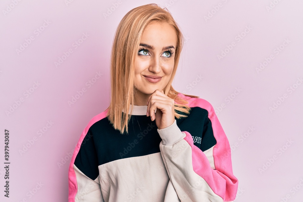 Beautiful caucasian woman wearing casual sporty jacket thinking concentrated about doubt with finger on chin and looking up wondering Beautiful caucasian woman wearing casual sporty jacket thinking concentrated about doubt with finger on chin and looking up wondering