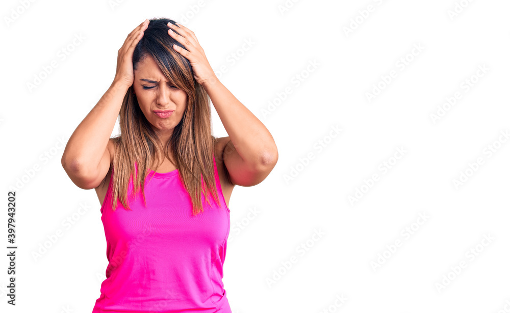 Young beautiful woman wearing sportswear suffering from headache desperate and stressed because pain and migraine. hands on head. Young beautiful woman wearing sportswear suffering from headache desperate and stressed because pain and migraine. hands on head.