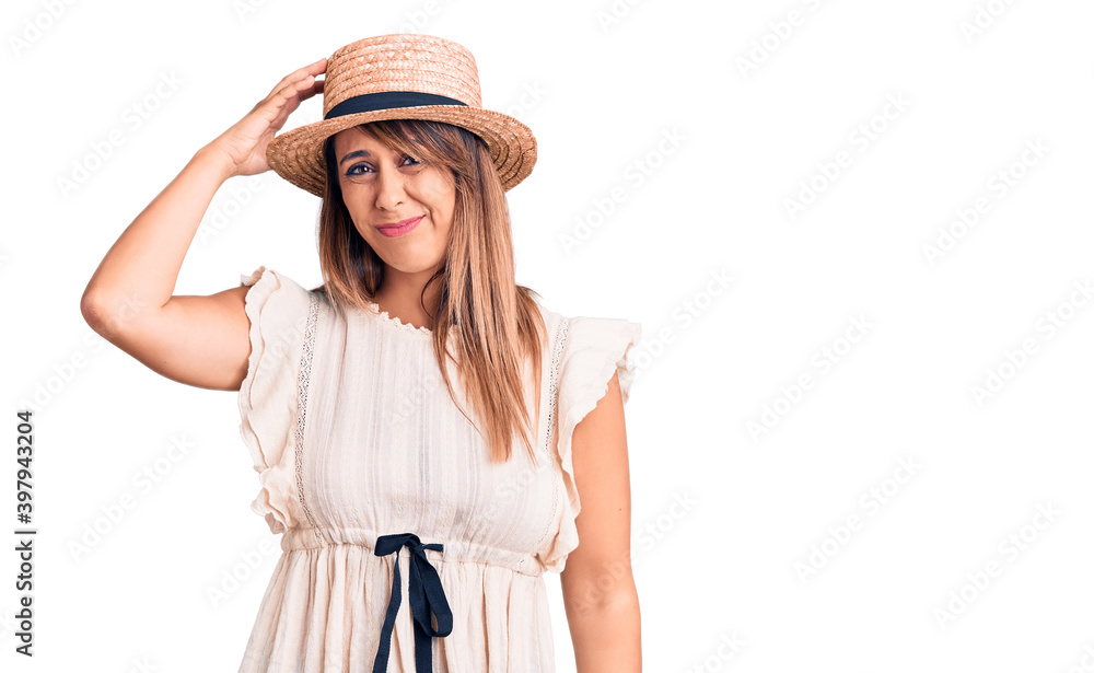 Young beautiful woman wearing summer hat and t-shirt confuse and wonder about question. uncertain with doubt, thinking with hand on head. pensive concept. Young beautiful woman wearing summer hat and t-shirt confuse and wonder about question. uncertain with doubt, thinking with hand on head. pensive concept.