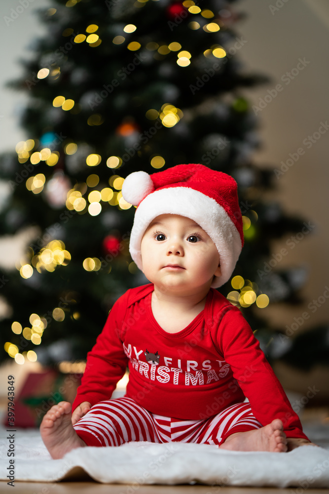 adorable little baby boy in a santa costume sitting on a soft fake fur in front of a christmas tree adorable little baby boy in a santa costume sitting on a soft fake fur in front of a christmas tree