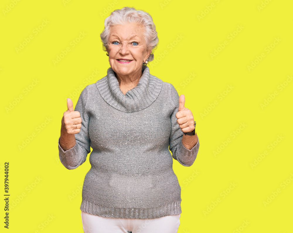 Senior grey-haired woman wearing casual winter sweater success sign doing positive gesture with hand, thumbs up smiling and happy. cheerful expression and winner gesture. Senior grey-haired woman wearing casual winter sweater success sign doing positive gesture with hand, thumbs up smiling and happy. cheerful expression and winner gesture.
