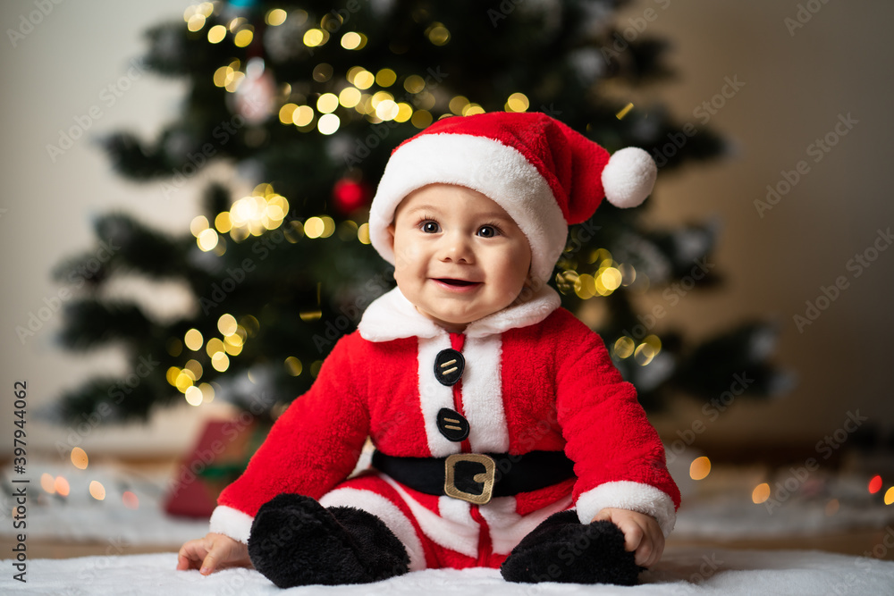 adorable little baby boy in a santa costume sitting on a soft fake fur in front of a christmas tree adorable little baby boy in a santa costume sitting on a soft fake fur in front of a christmas tree