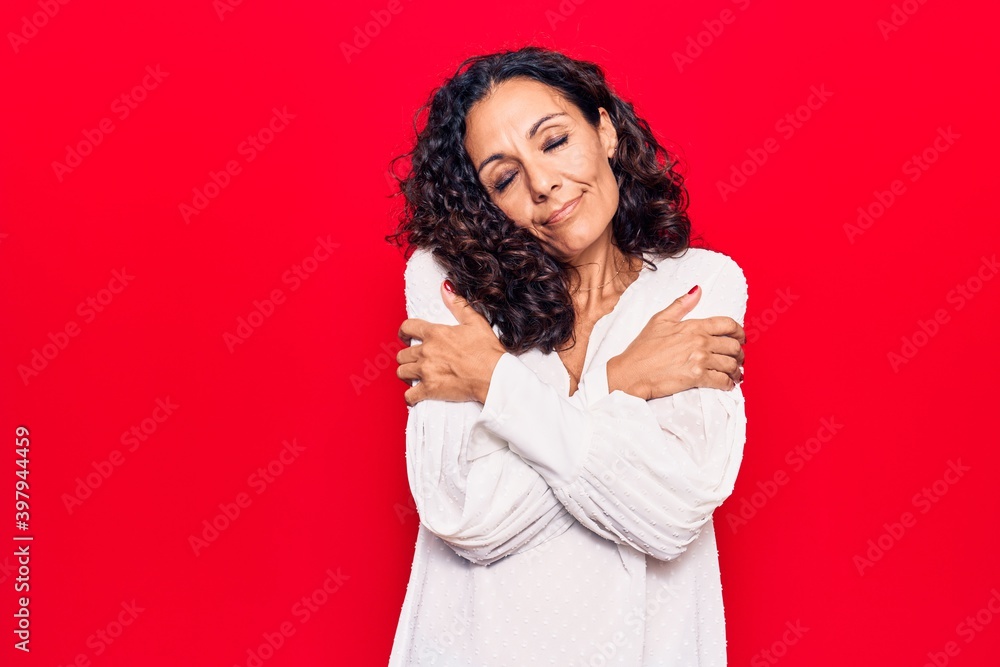 Middle age beautiful woman wearing casual shirt hugging oneself happy and positive, smiling confident. self love and self care Middle age beautiful woman wearing casual shirt hugging oneself happy and positive, smiling confident. self love and self care