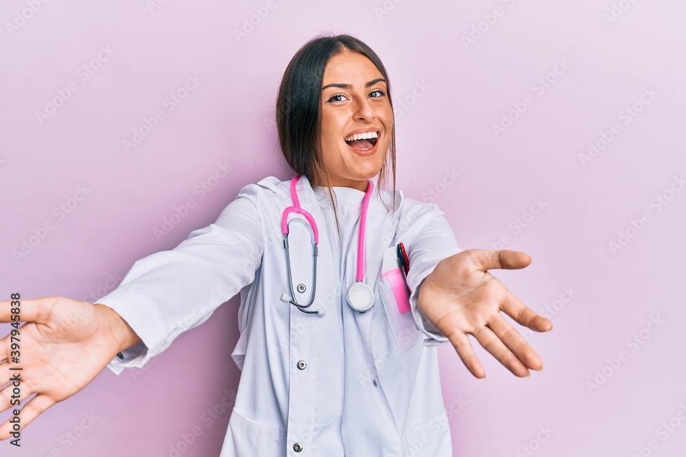 Beautiful hispanic woman wearing doctor uniform and stethoscope looking at the camera smiling with open arms for hug. cheerful expression embracing happiness. Beautiful hispanic woman wearing doctor uniform and stethoscope looking at the camera smiling with open arms for hug. cheerful expression embracing happiness.