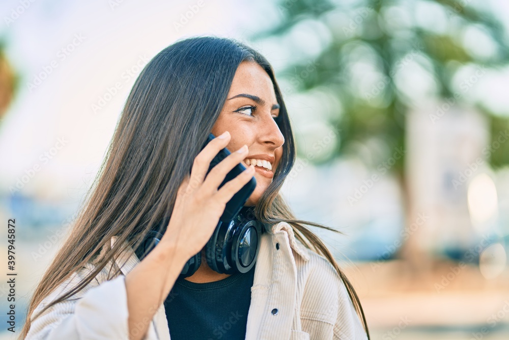 Young hispanic girl smiling happy talking on the smartphone and using headphones at the city. Young hispanic girl smiling happy talking on the smartphone and using headphones at the city.