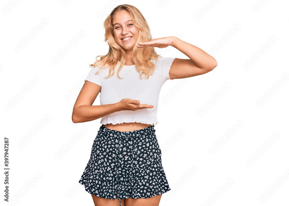 Young blonde girl wearing casual white tshirt gesturing with hands showing big and large size sign, measure symbol. smiling looking at the camera. measuring concept. Young blonde girl wearing casual white tshirt gesturing with hands showing big and large size sign, measure symbol. smiling looking at the camera. measuring concept.