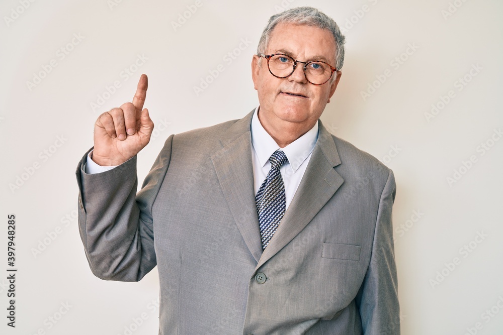 Senior grey-haired man wearing business suit smiling with an idea or question pointing finger up with happy face, number one Senior grey-haired man wearing business suit smiling with an idea or question pointing finger up with happy face, number one
