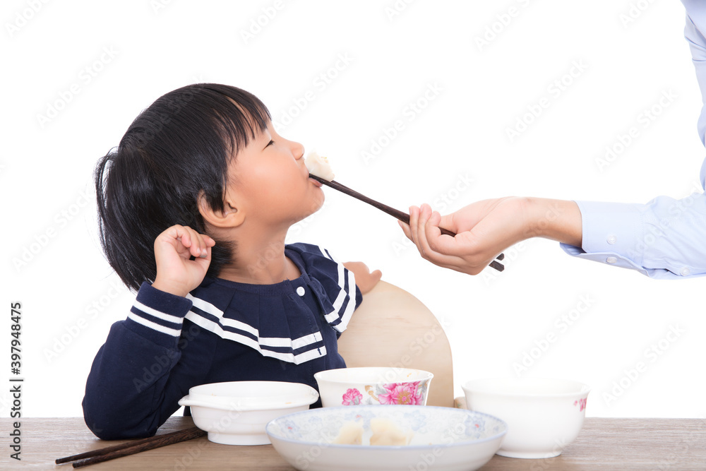 Mother is feeding children dumplings on the table in front of white background Mother is feeding children dumplings on the table in front of white background