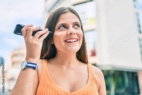 Free Download Young middle east girl smiling happy listening audio message using smartphone at the city. - GFXLoad