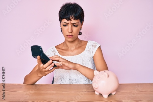 Beautiful brunettte woman caculating money savings skeptic and nervous, frowning upset because of problem. negative person. photo