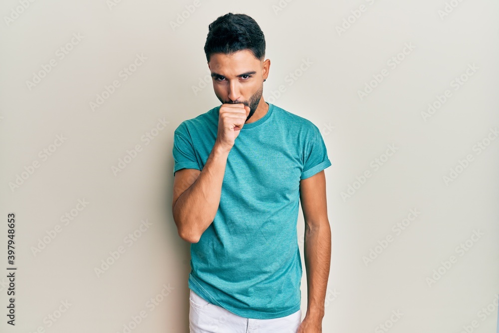 Young man with beard wearing casual clothes feeling unwell and coughing as symptom for cold or bronchitis. health care concept. Young man with beard wearing casual clothes feeling unwell and coughing as symptom for cold or bronchitis. health care concept.