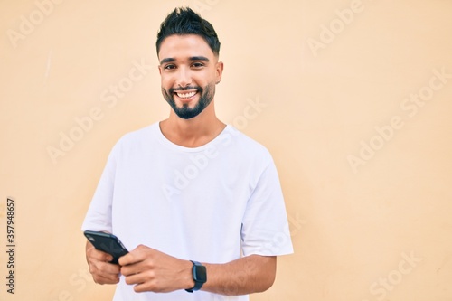Young arab man smiling happy using smartphone at the city. © Krakenimages.com