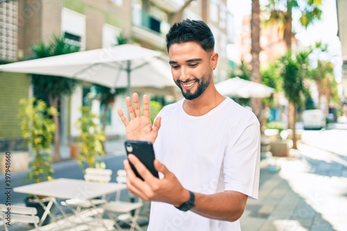 Young arab man smiling happy doing video call using smartphone at the city.