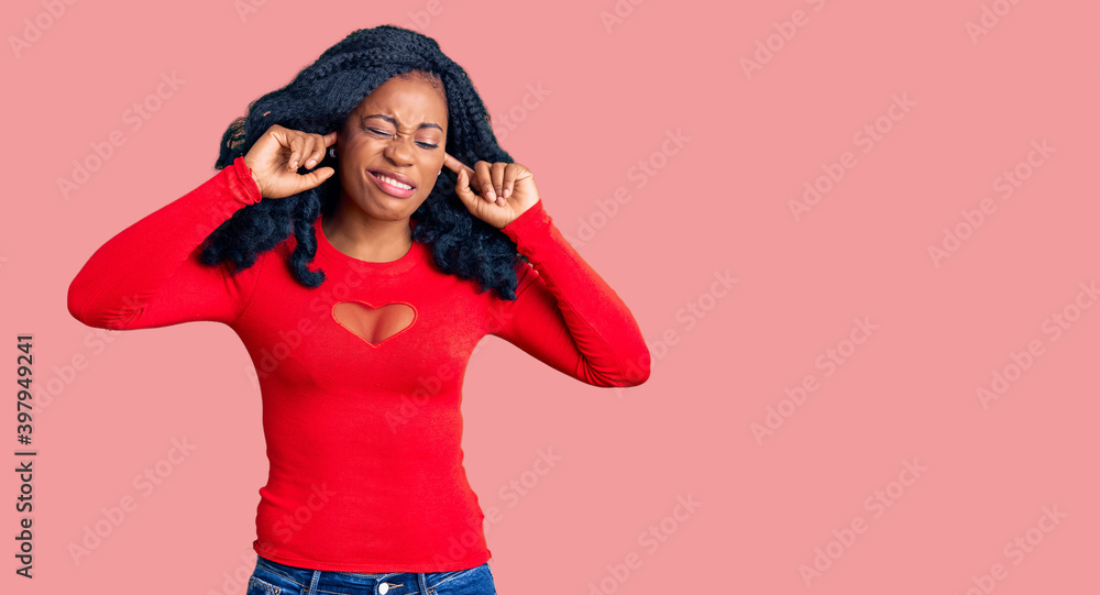 Beautiful african american woman wearing casual clothes covering ears with fingers with annoyed expression for the noise of loud music. deaf concept. Beautiful african american woman wearing casual clothes covering ears with fingers with annoyed expression for the noise of loud music. deaf concept.