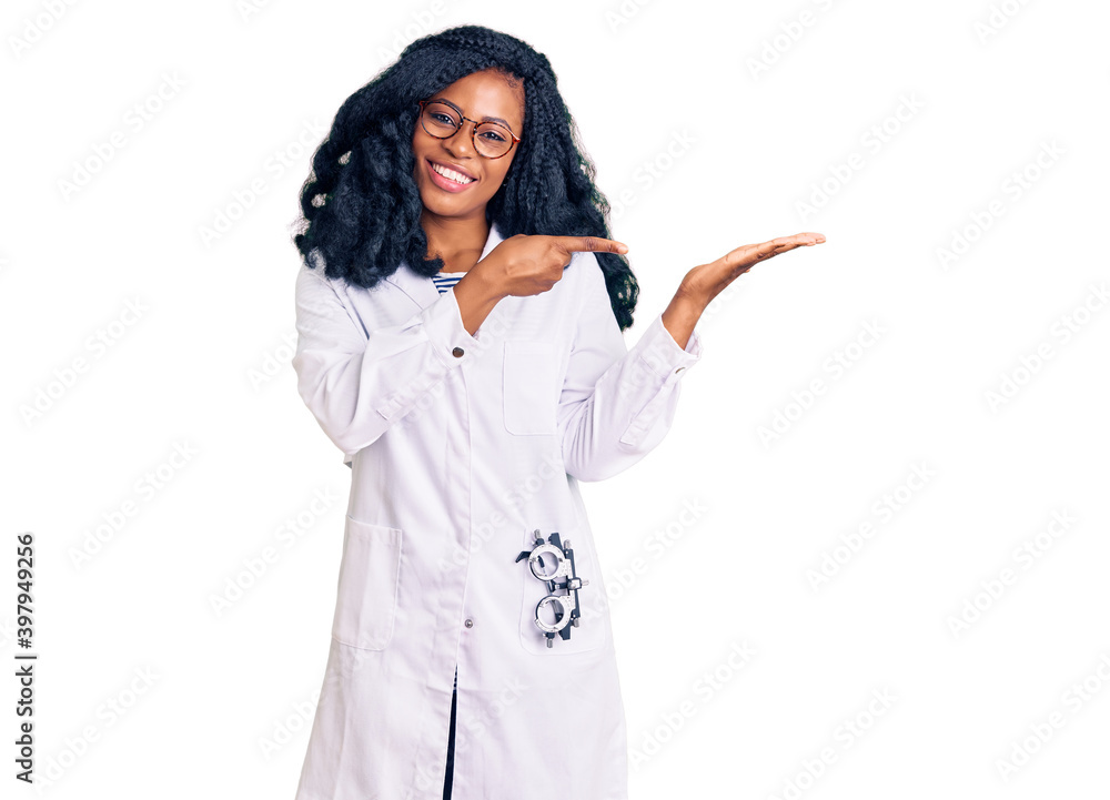 Beautiful african american optician woman with optometry glasses amazed and smiling to the camera while presenting with hand and pointing with finger. Beautiful african american optician woman with optometry glasses amazed and smiling to the camera while presenting with hand and pointing with finger.