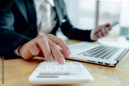 Close up of Business man working in finance and accounting Analyze financial budget with calculator and laptop computer in the office