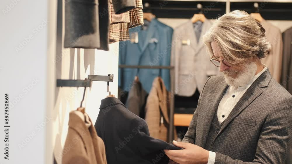 Businessman choosing a suit in a luxury shop against the backdrop of suits,shirts and jackets. Businessman choosing a suit in a luxury shop against the backdrop of suits,shirts and jackets.