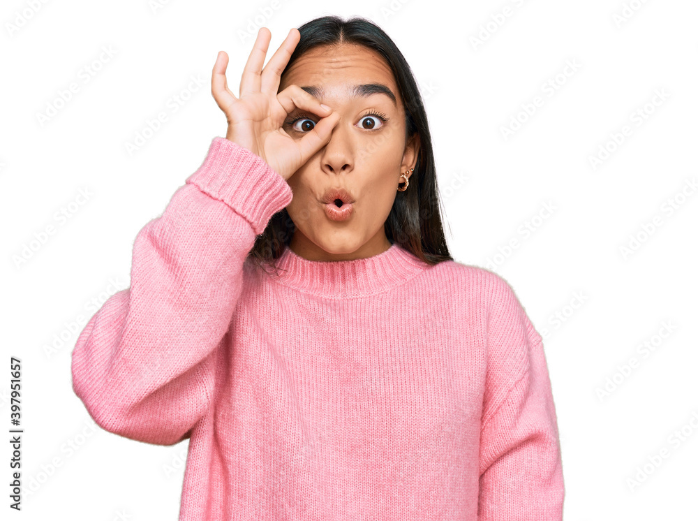 Young asian woman wearing casual winter sweater doing ok gesture shocked with surprised face, eye looking through fingers. unbelieving expression. Young asian woman wearing casual winter sweater doing ok gesture shocked with surprised face, eye looking through fingers. unbelieving expression.